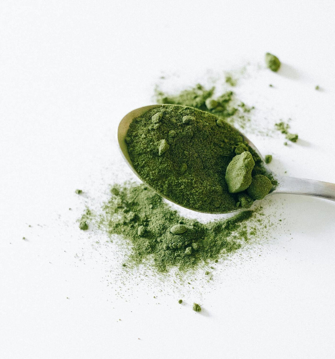 Cuillère contenant de la poudre de matcha sur une table blanche